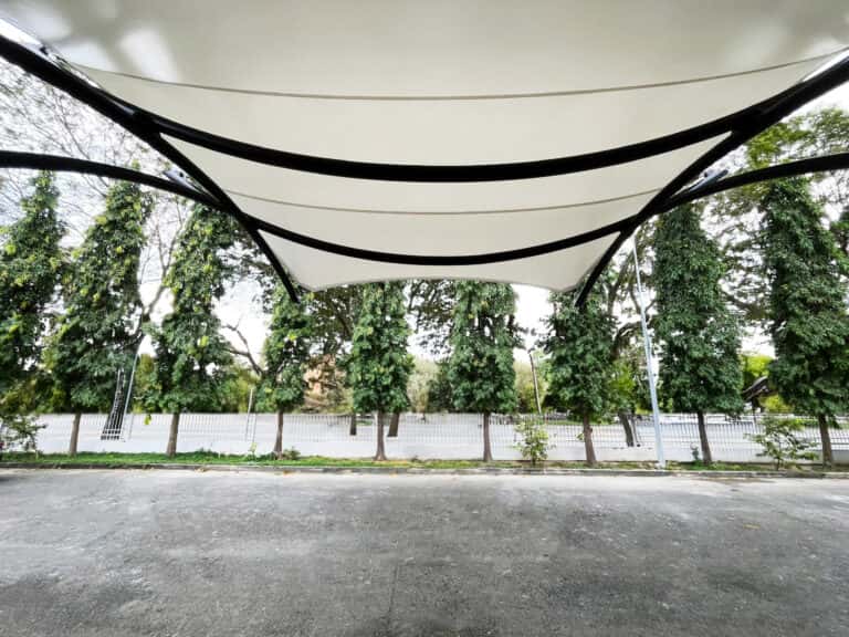 Clientes disfrutando de la sombra en la terraza de la cafetería bajo la cubierta.