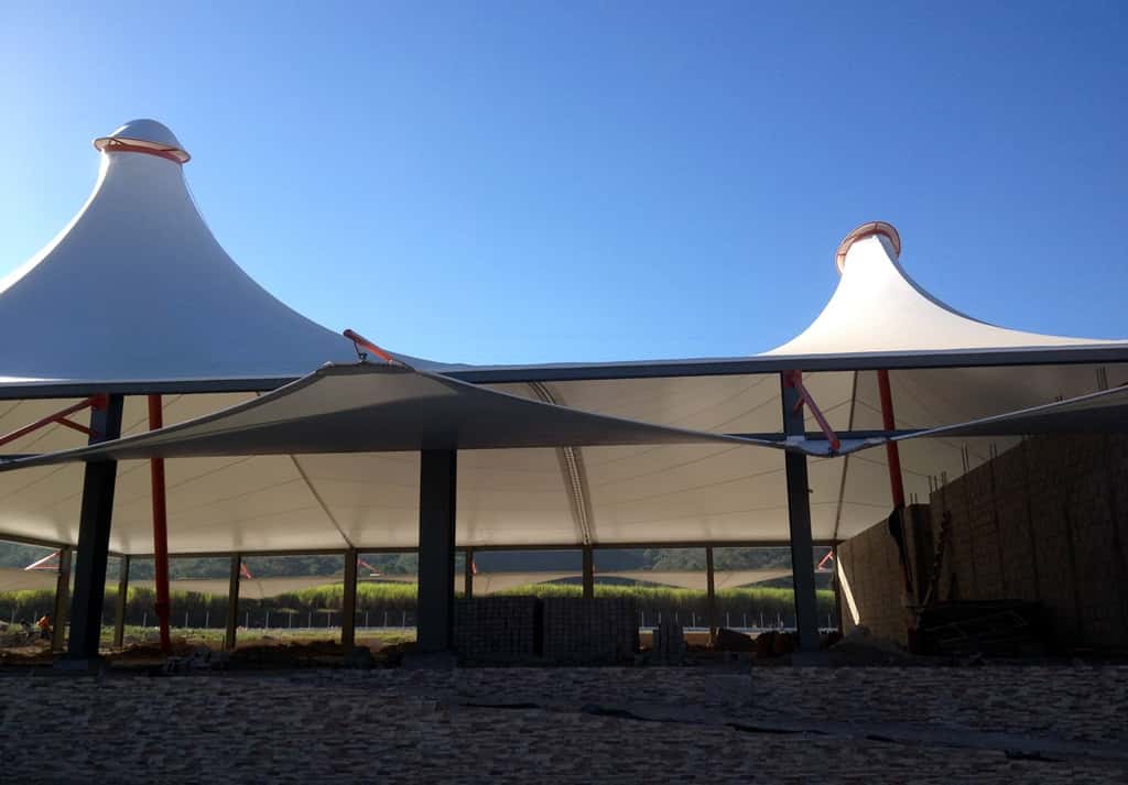 Estructura de mallasombra protegiendo una zona de picnic en un área recreativa.