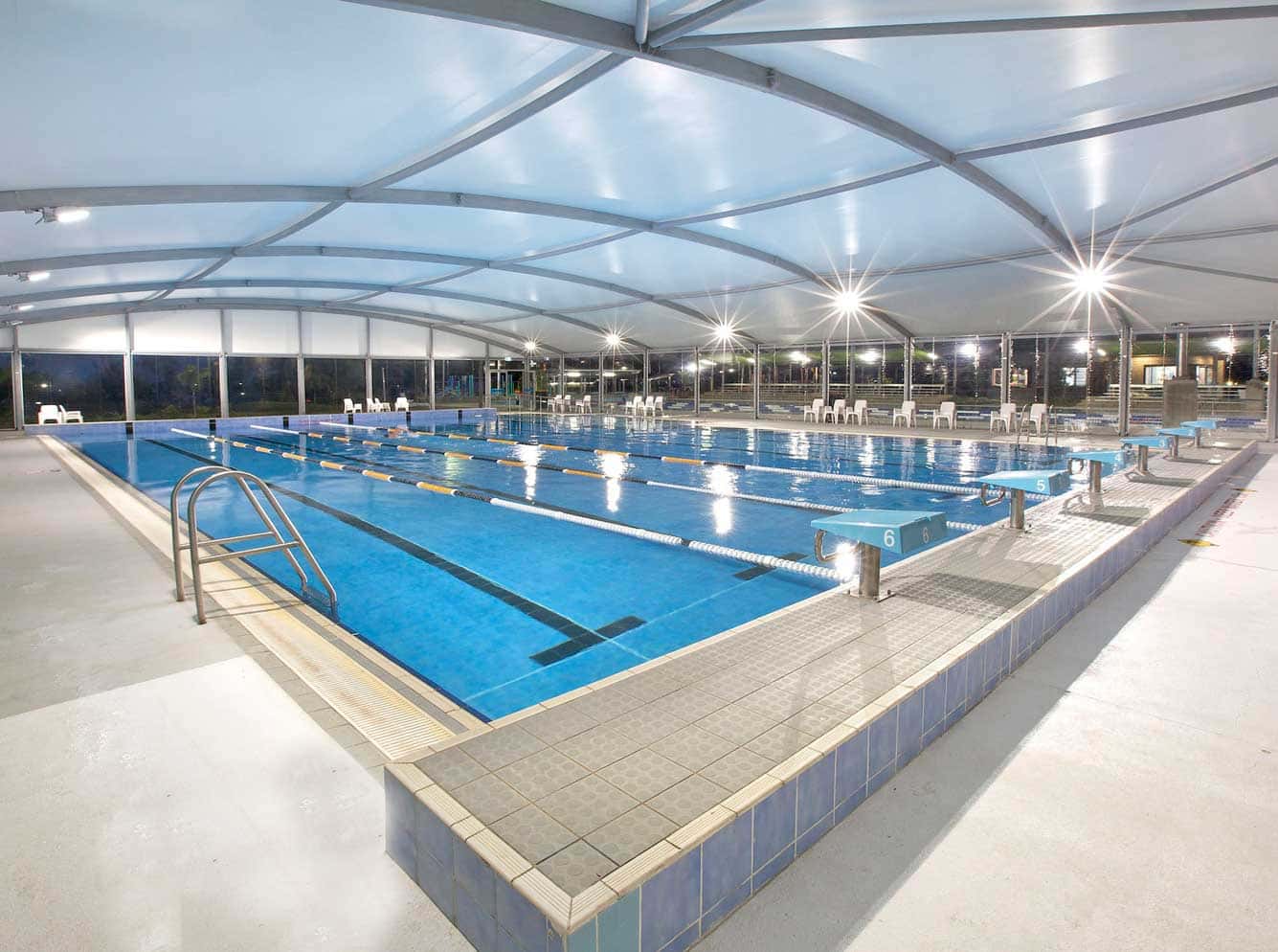 Zona de descanso con sombra bajo una tensoestructura en un club de lujo.