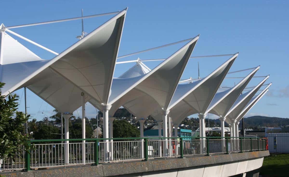 Peatones caminando bajo la protección de las tensoestructuras del puente.